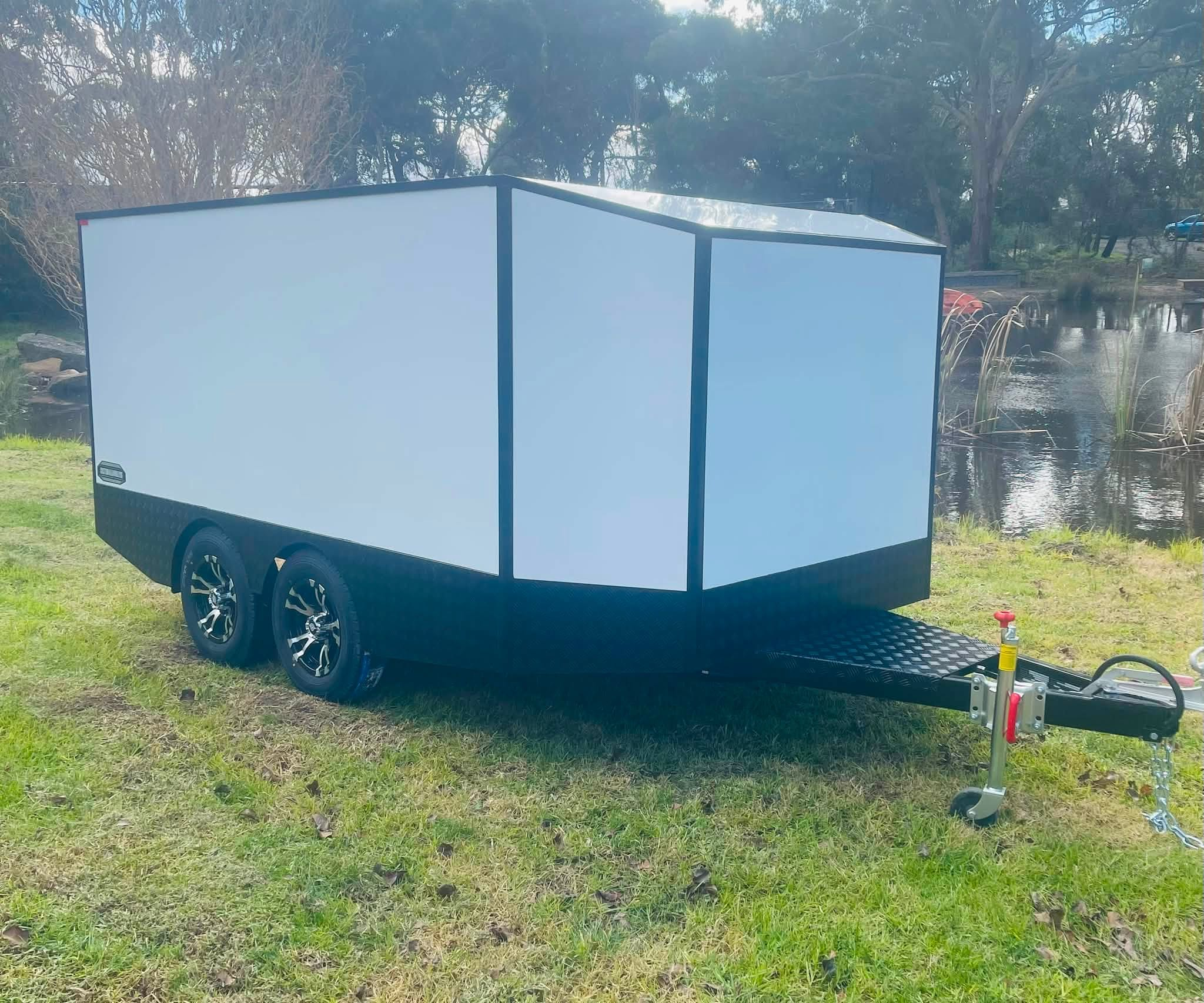 White tandem custom toy hauler beside a pond